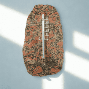 Luonnonkivestä valmistettu unakiitti-lämpömittari mustalla taustalla