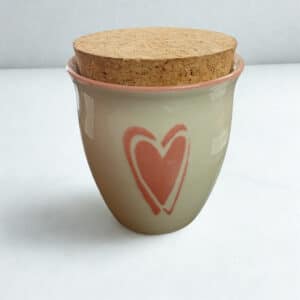 Pentikin keraaminen purkki korkkikannella ja vaaleanpunaisella sydänkoristeella vaalealla taustalla