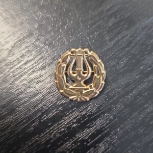 925 hopeinen lyyra-rintaneula mustaa puupintaa vasten.