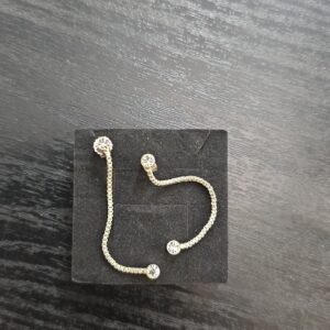 Hopeiset ketjuriippuvat kivikorvakorut mustalla korualustalla.