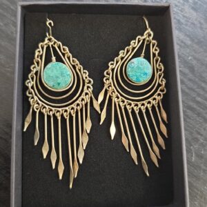 Boho-tyyliset metalliset korvakorut turkoosinsävyisillä kivillä mustassa rasiassa.